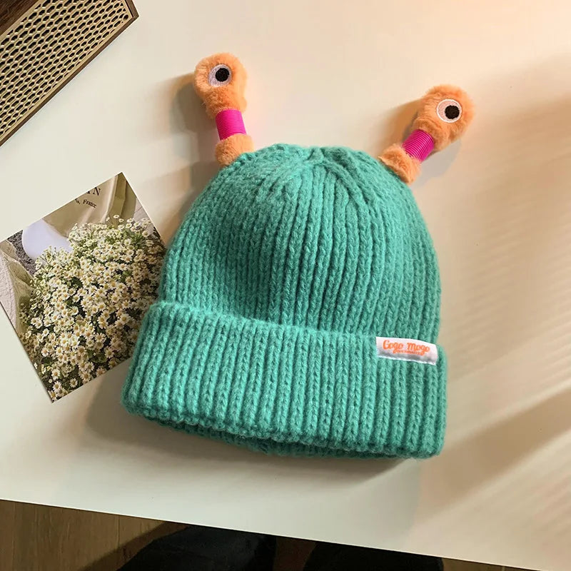 Green knit beanie with cartoonish antlers on a light surface