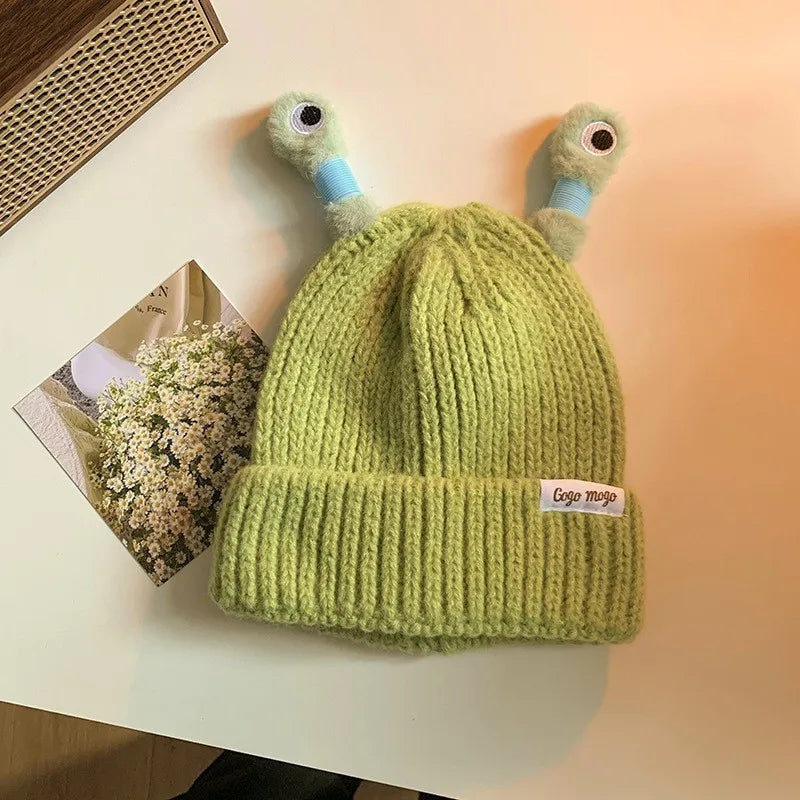 Green knitted hat with cartoonish duck face design on a blurred background