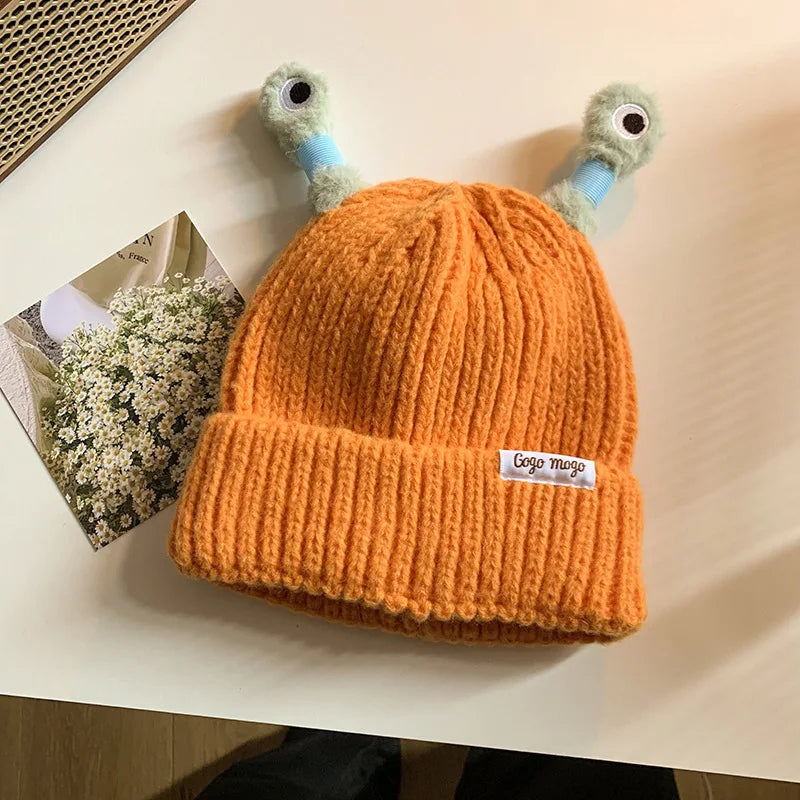 Orange knit beanie with cartoonish antlers on a light surface