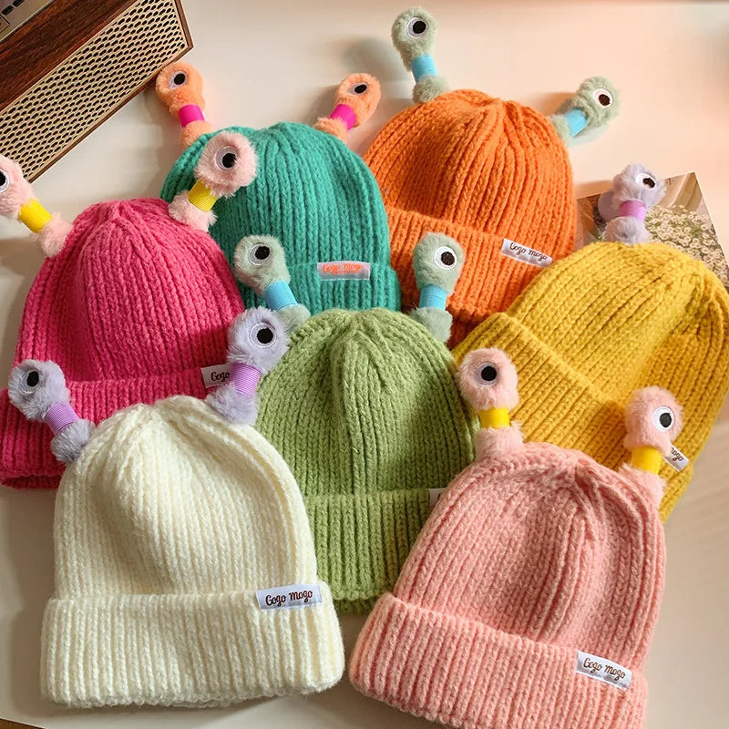 Colorful knit hats with cartoonish bird decorations on a light background
