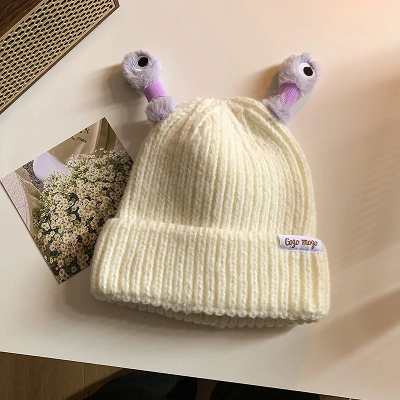 Cream-colored knit beanie with cartoonish duck ears on a light surface.